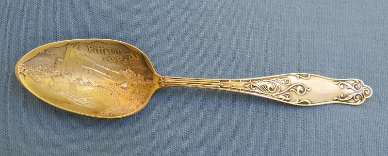 Souvenir Mining Spoon Pittston PA.JPG - SOUVENIR MINING SPOON PITTSTON PA - Sterling silver spoon, 4 3/4 in. long, engraved colliery mining scene in gold-washed bowl with marking PITTSTON PA., ca.1900, reverse with Sterling marking, maker’s mark and PAT 1892  [Pittston is a city located within Pennsylvania's Coal Region in Luzerne County. Situated between Scranton and Wilkes-Barre, the city gained prominence in the late 19th and early 20th centuries as an active anthracite coal mining city, drawing a large portion of its labor force from European immigrants. The population was 7,739 as of the 2010 census, making it the fourth largest city in Luzerne County. At its peak in 1920, the population of Pittston was 18,497.  The first discovery of anthracite coal in the Wyoming Valley occurred around 1770. The first mine was established in 1775 near Pittston. With the opening of a canal in the 1830s, Pittston became an important link in the coal industry. The anthracite and railroad industry attracted thousands of immigrants, making Pittston a true melting pot with once-distinct ethnic and class neighborhoods. The population of Pittston boomed in the late 19th century. The boom continued well into the 20th century. The anthracite coal mining industry, and its extensive use of child labor in the early part of the 20th century, was one of the industries targeted by the National Child Labor Committee and its hired photographer, Lewis Hine. Many of Hine's subjects were photographed in the mines and coal fields in and around Pittston between 1908 and 1912. The impact of the Hine photographs led to the enactment of child labor laws across the country.  Anthracite coal mining remained a major industry in the Pittston region until the Knox Mine Disaster. It essentially killed the industry in Northeastern Pennsylvania. On January 22, 1959, the ice-laden Susquehanna River broke through the roof of the River Slope Mine of the Knox Coal Company in nearby Port Griffith. This allowed for billions of gallons of river water to flood the interconnected mines. It took three days to plug the hole in the riverbed, which was done by dumping large railroad cars, smaller mine cars, culm, and other debris into the whirlpool formed by the water draining into the mine.  Sixty-nine miners escaped; twelve miners died and their bodies were never recovered.]